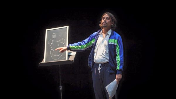 Fabrizio Martorelli che indica una lavagna appoggiata su un leggio raffigurante peppa pig e una casetta